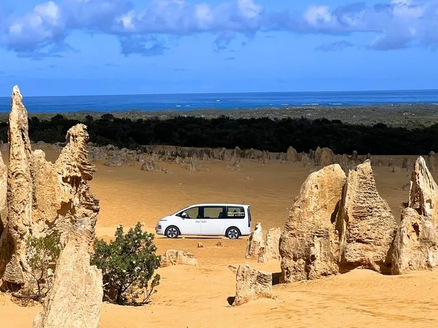 Van turistico bianco parcheggiato tra le formazioni calcaree nel Deserto dei Pinnacoli.